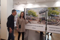 Oliver Simon und Astrid Ißleib neben Aufstellern mit Elberfeld-Visualisierungen im Baustellen-Info-Büro in Elberfeld.